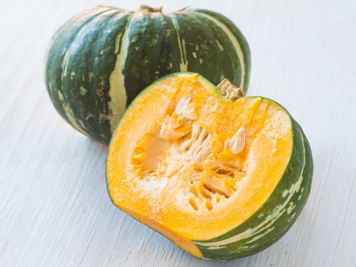 Half-sliced kabocha squash on a white table